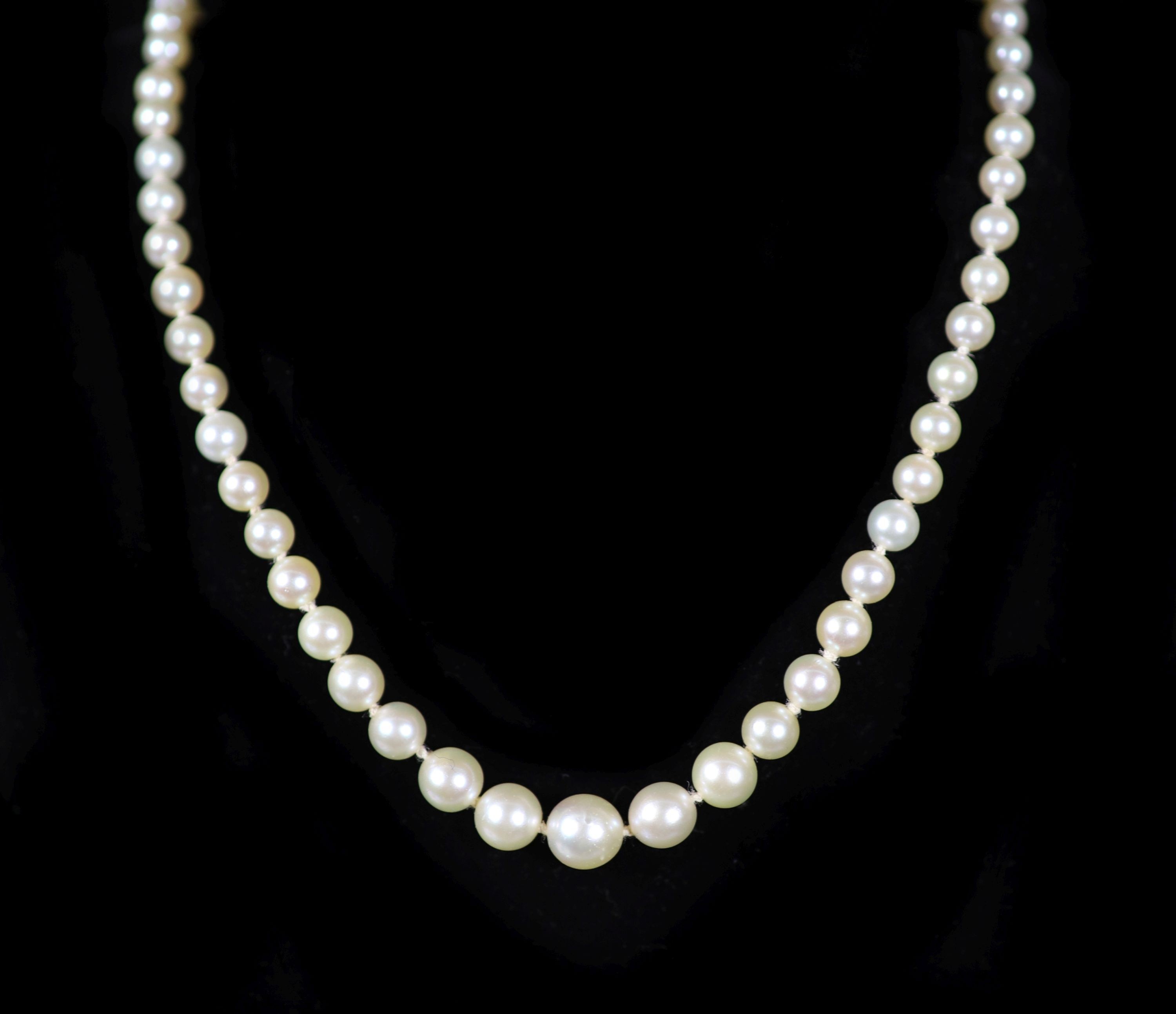 A mid 20th century single strand graduated pearl necklace, with platinum and diamond set open work clasp, signed Cartier with indistinct numbers